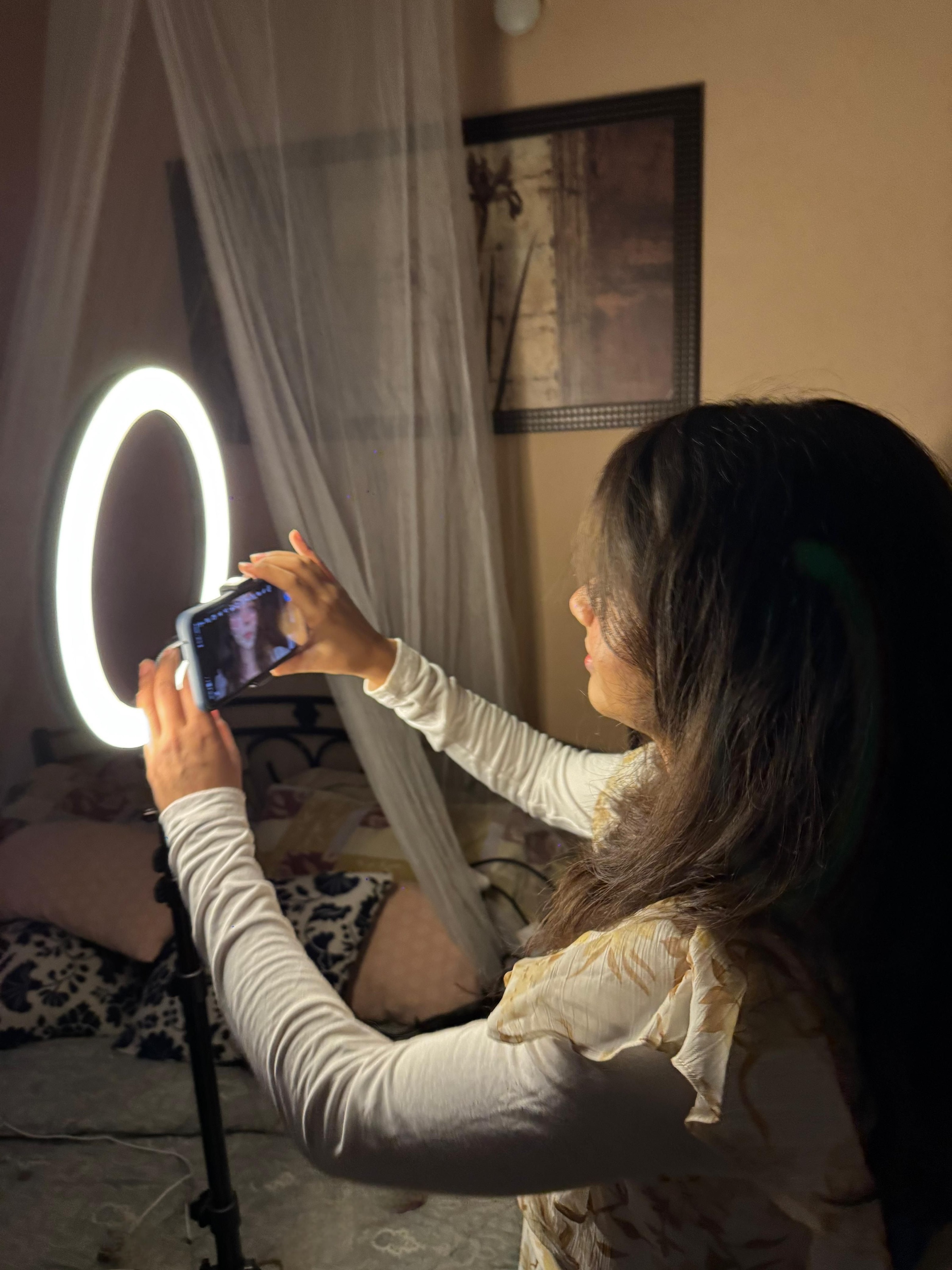 Woman setting up a ring light and phone in her bedroom