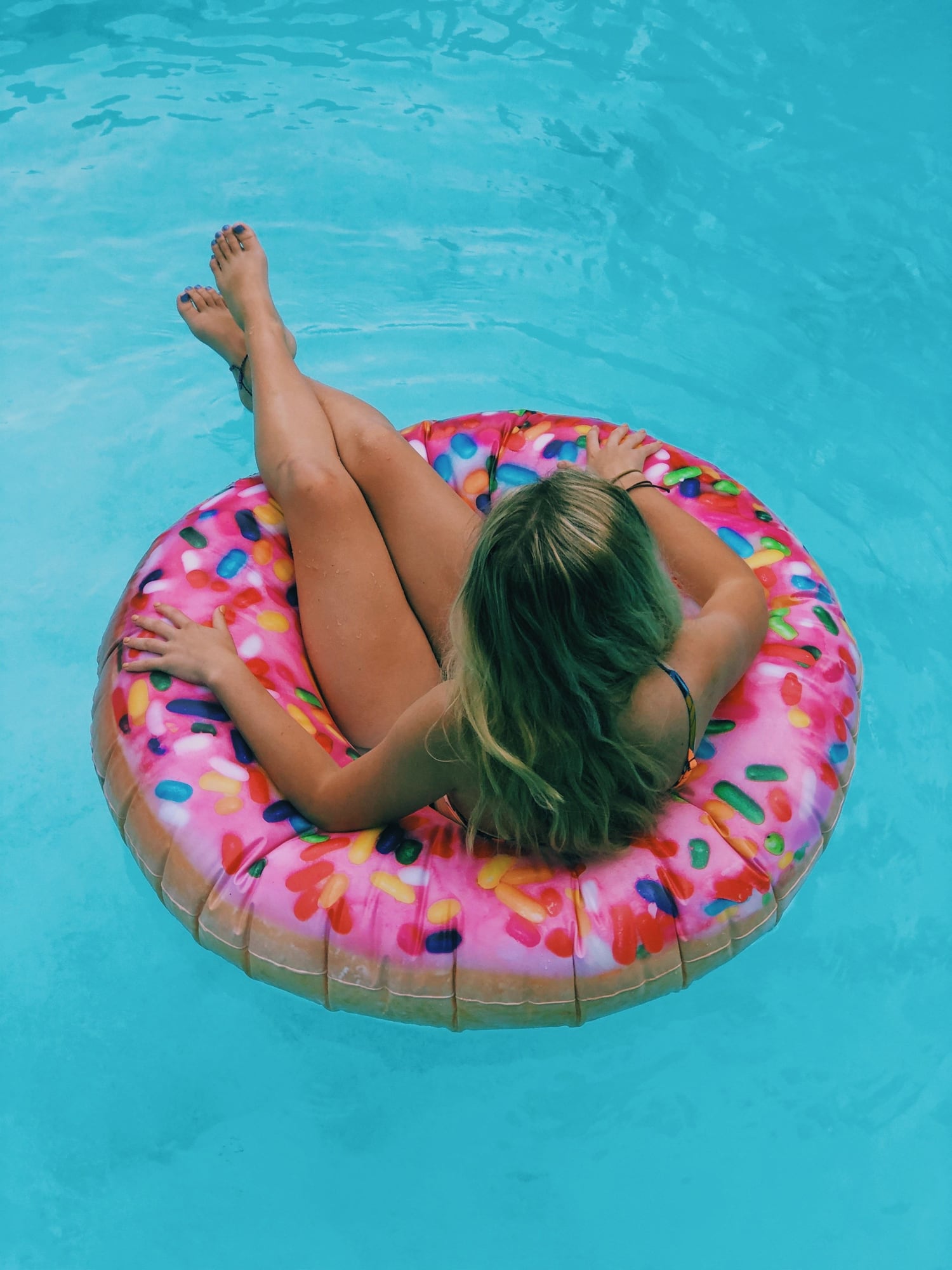 Woman lying on a doughnut pool float, seen from above