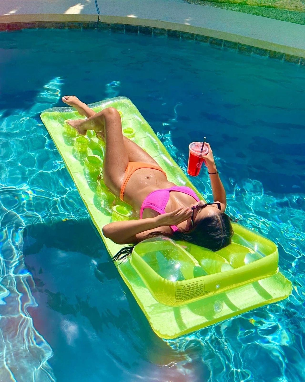 Woman relaxing on a pool float with a drink