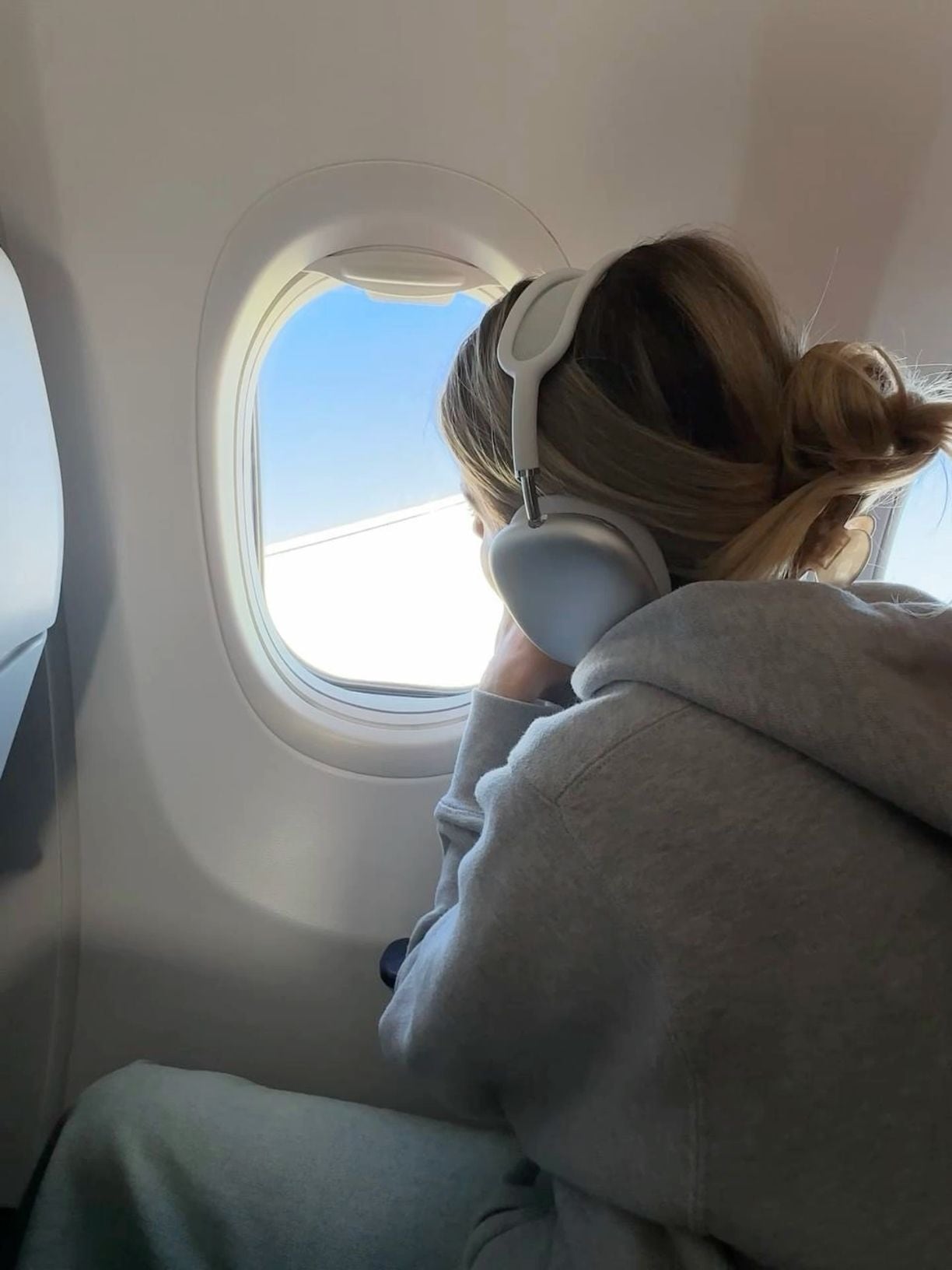 Woman in headphones looking out of a plane window