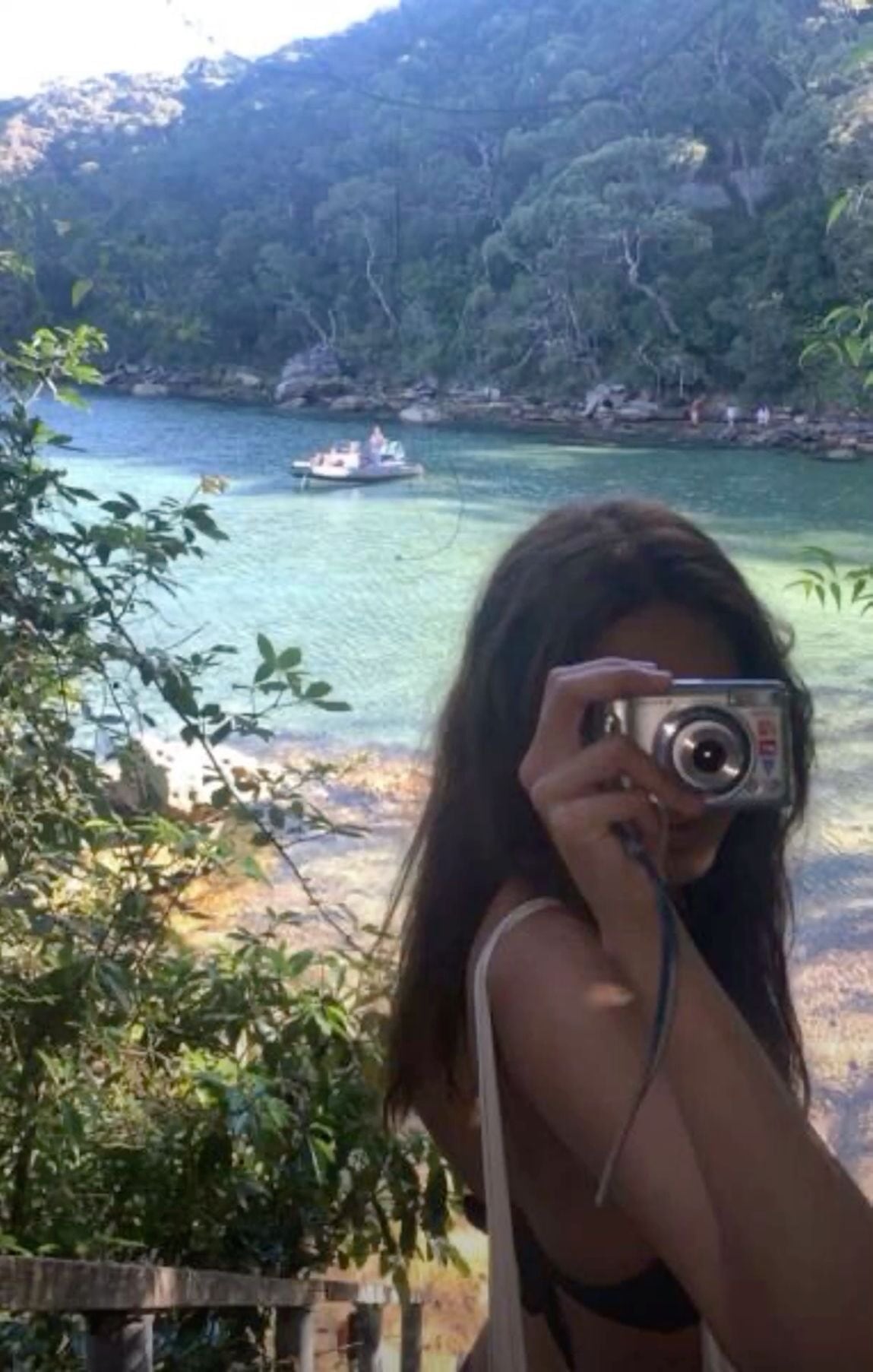 Woman taking a photo with a camera by a turquoise bay
