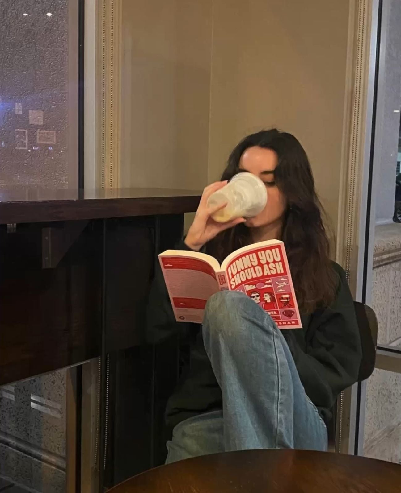 Woman reading a book while drinking from a mug