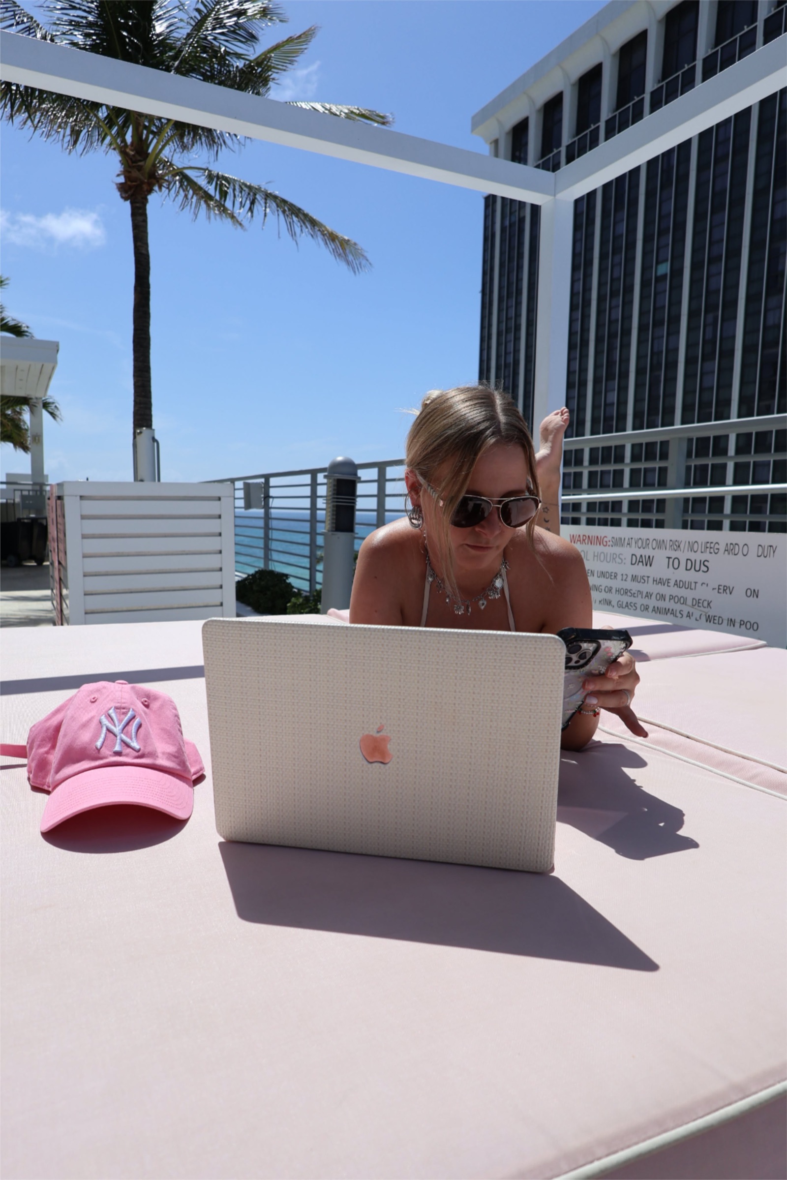 Woman in sunglasses working on a laptop at a sunny rooftop table