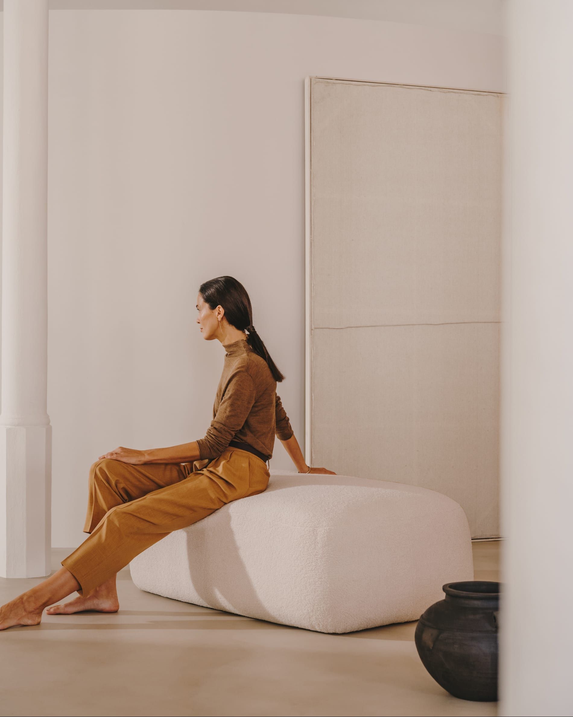 Woman sitting on a white bench in a calm, minimal room