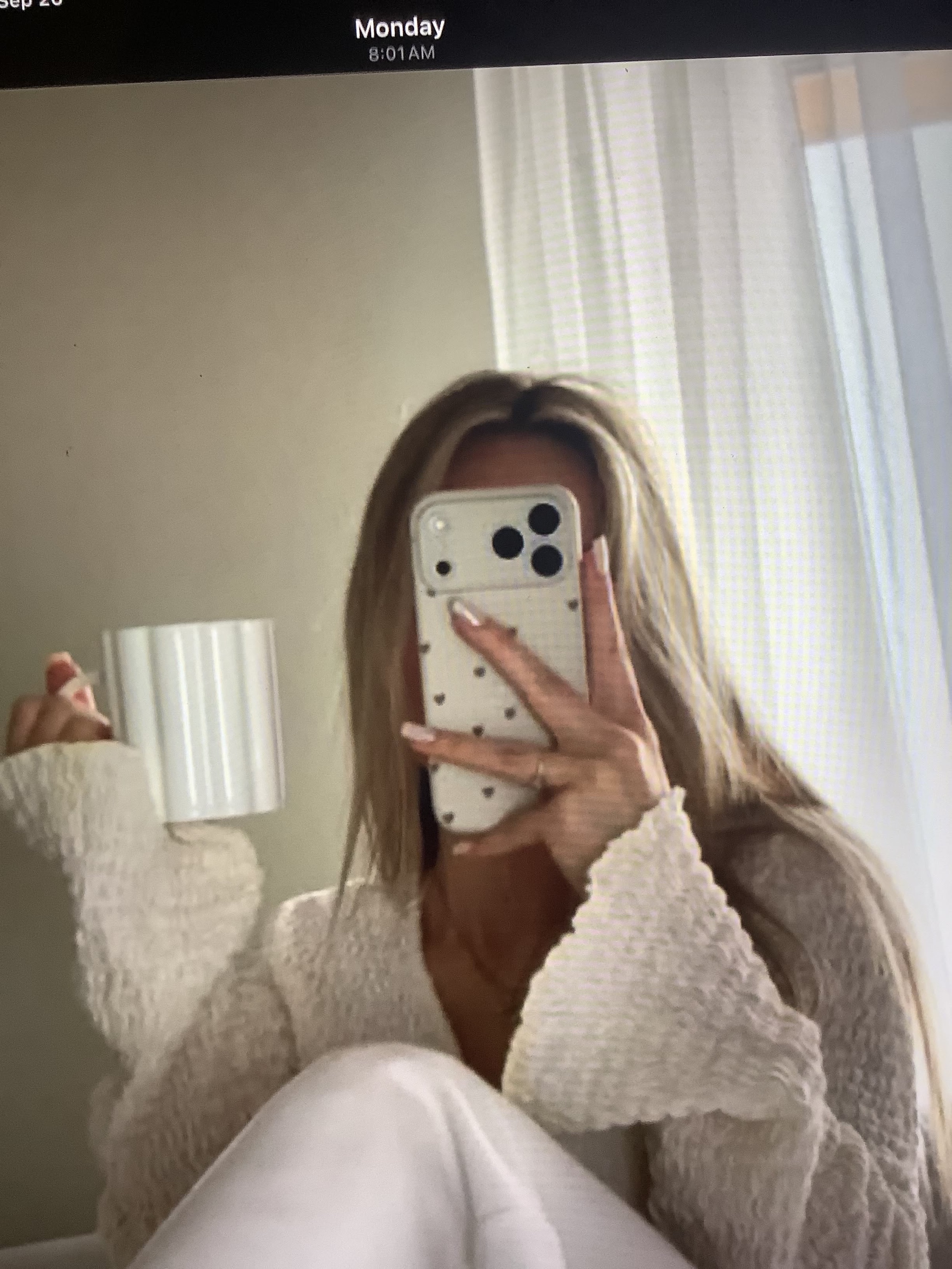 Woman hiding her face behind her phone in a mirror selfie