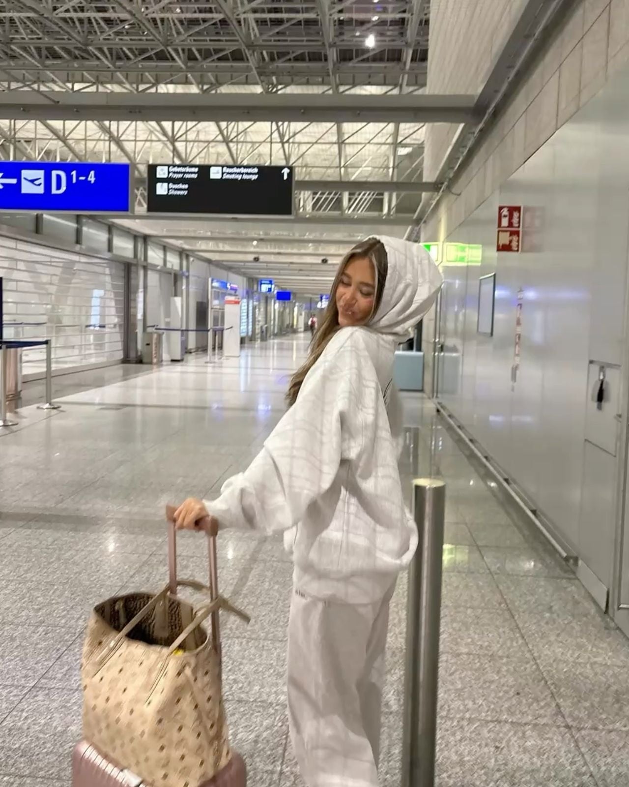 Woman in a white hoodie with her hood up at an airport