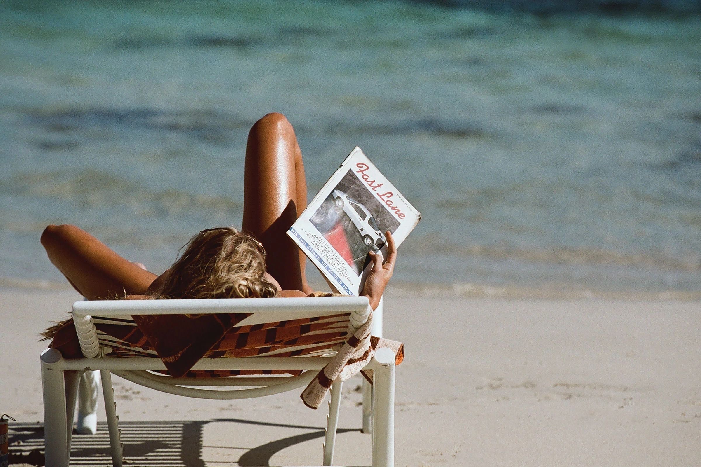Woman reading on a beach lounger by the sea